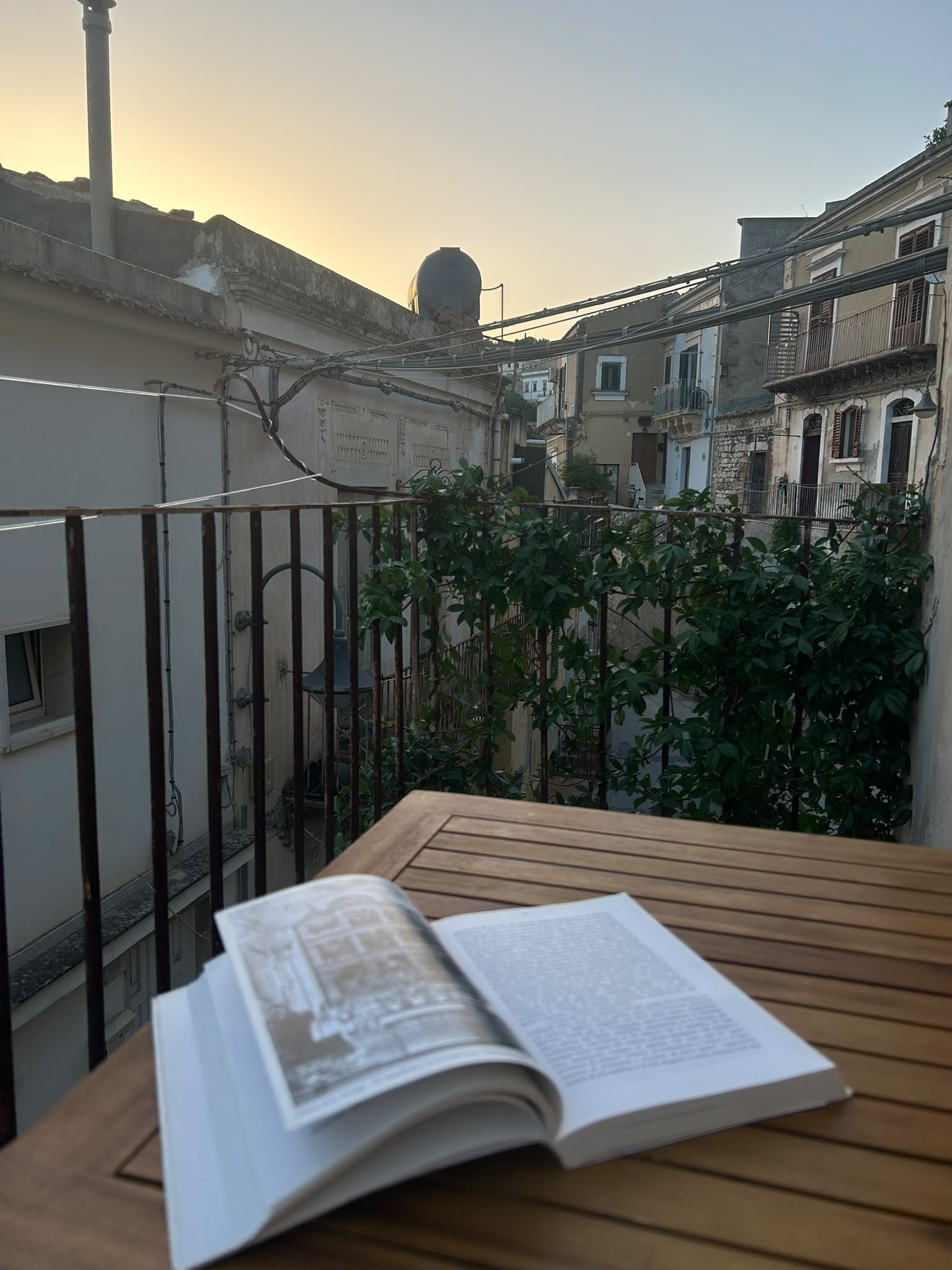Terrazza di Maltese16 con tavolino, libro e vista sui tetti di Modica al tramonto