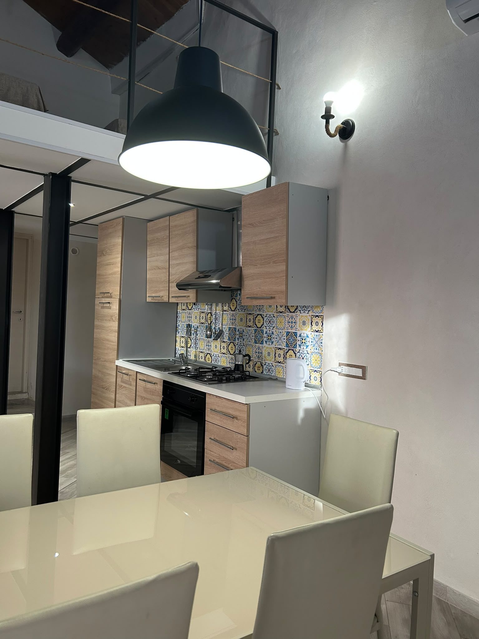 Zona pranzo con tavolo, sedie e soppalco a vista